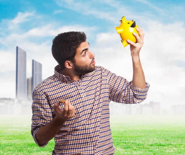 Lovely man looking in yellow piggy bank